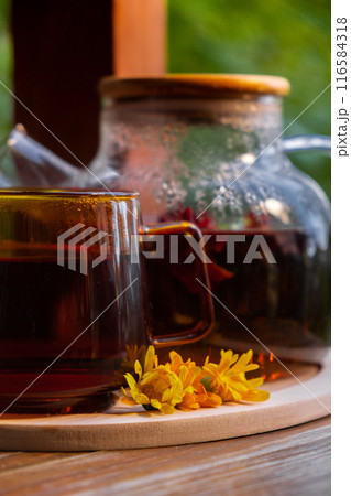 Calendula flower healthy tea in glass mug with tea pot on garden table. Herbal medicine Delicious tisane tea with fresh yellow blossom dandelion flowers tea cup. Green clearing infusion Wildflowers 116584318