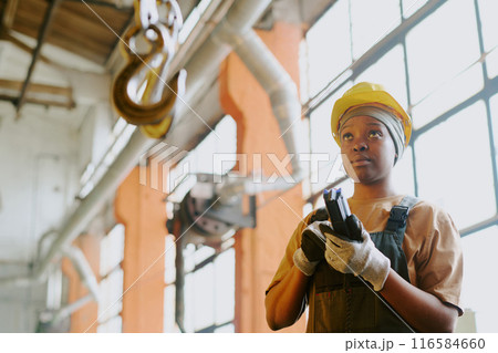 Young African American woman operating lifting equipment at work in modern factory, copy space Young African American woman operating lifting equipment at work in modern factory, copy space 116584660