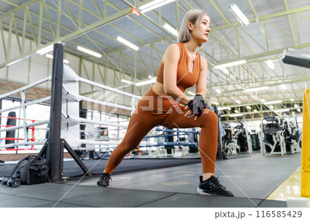 Young woman stretching her legs before starting her morning work out at a local gym Young woman stretching her legs before starting her morning work out at a local gym 116585429