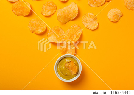 Potato chips with mustard on a yellow background Potato chips with mustard on a yellow background 116585440