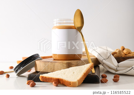 Peanut paste in a glass jar with a spoon, on a light background. 116585522