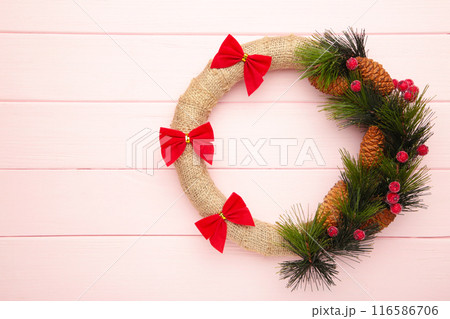 Green christmas wreath decorated with red bow on pink background. Thanksgiving Day. 116586706