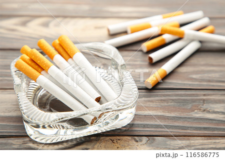 Cigarettes in ashtray on grey wooden background. 116586775