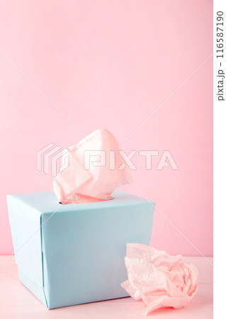 Blue box with paper tissues and used crumpled napkins on pink background. 116587190