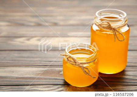 Jar of honey on grey wooden table. Jar of honey on grey wooden table. 116587206