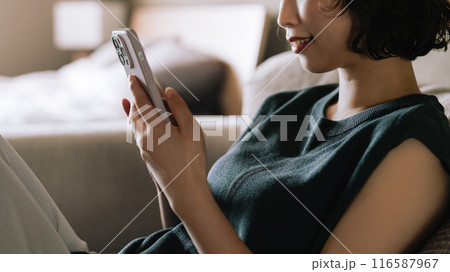 ソファでスマホを使う笑顔の日本人女性 ソファでスマホを使う笑顔の日本人女性 116587967