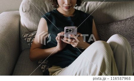 ソファでスマホを使う笑顔の日本人女性 ソファでスマホを使う笑顔の日本人女性 116587968