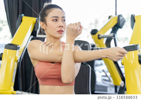 Young woman stretching her arms and upper body before starting her morning work out at a local gym 116588633