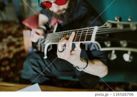 High angle view of bearded rock musician wearing red sunglasses playing electric guitar 116588706