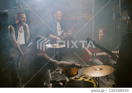 Group of joyful men and woman playing in music band having rehearsal in garage studio 116588910