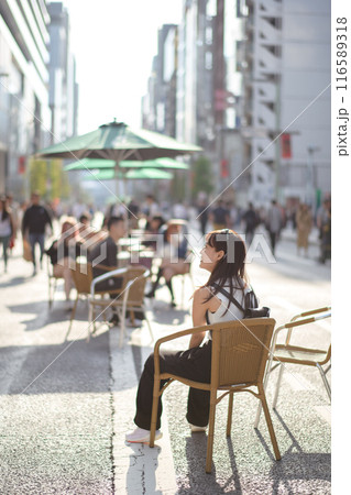Experience urban joy in Tokyo, a happy asian woman enjoying city bench. 116589318