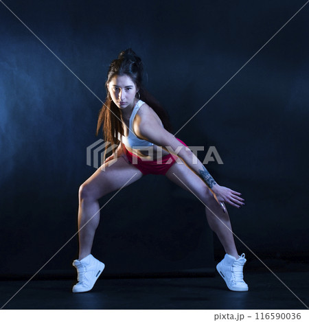 Beautiful athletic girl in sportswear on a dark background Beautiful athletic girl in sportswear on a dark background 116590036