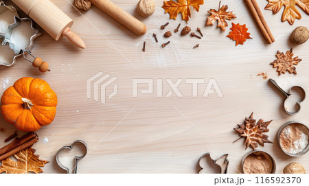 Autumn baking background with a rolling pin, cookie cutters shaped like leaves, cinnamon sticks, and a small pumpkin 116592370