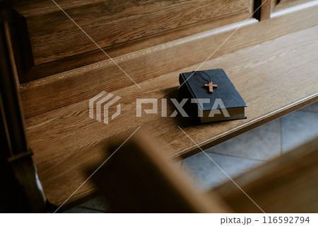 High angle view no people shot of Bible book with cross on wooden pew in Catholic church High angle view no people shot of Bible book with cross on wooden pew in Catholic church 116592794