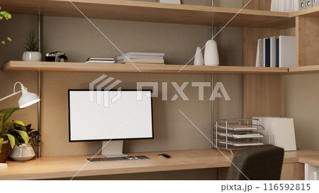 A computer with a white-screen mockup on a wooden desk in a cozy home office. 116592815