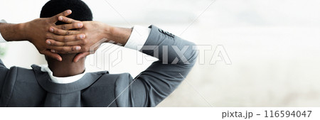 Back view of african american businessman leaning back, resting over white wall background, panorama with copy space Back view of african american businessman leaning back, resting over white wall background, panorama with copy space 116594047