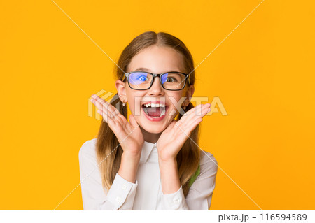 Wow, Back To School. Happy Schoolgirl Shouting In Delight Holding Hands Near Mouth On Yellow Background. Studio Shot, Empty Space 116594589
