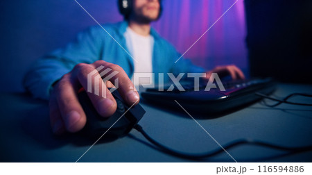 A close-up image of a gamers hand using a computer mouse while playing a game on their desktop. The focus is on the hand and the mouse, cropped A close-up image of a gamers hand using a computer mouse while playing a game on their desktop. The focus is on the hand and the mouse, cropped 116594886