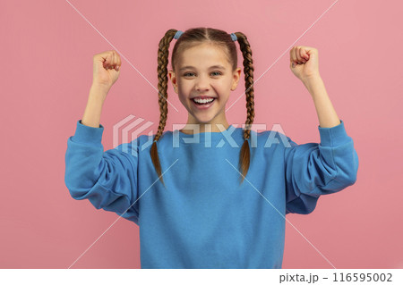 A cheerful young girl with braided hair is raising her fists in the air in a gesture of triumph or excitement, her joyful expression conveys a sense of victory or celebration 116595002