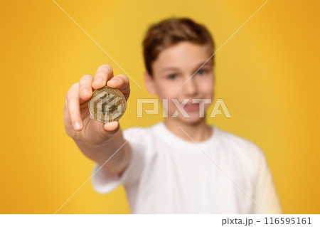 Cryptocurrency and modern finance. Cheerful boy holding golden bitcoin, orange studio background Cryptocurrency and modern finance. Cheerful boy holding golden bitcoin, orange studio background 116595161