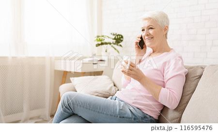 Cheerful senior lady having phone call on her smartphone and gossiping, enjoying fresh tea, free space Cheerful senior lady having phone call on her smartphone and gossiping, enjoying fresh tea, free space 116595476