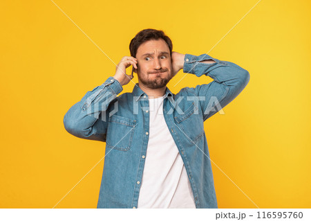 Puzzled man wearing a blue shirt is engaged in a phone conversation, holding a cell phone to his ear. He appears focused and attentive, possibly discussing important matters. 116595760