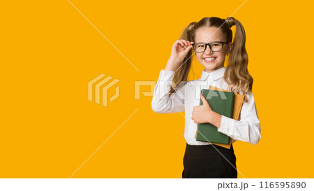 First grade concept. Portrait of cute little girl holding schoolbooks over yellow studio background. Free space for text First grade concept. Portrait of cute little girl holding schoolbooks over yellow studio background. Free space for text 116595890