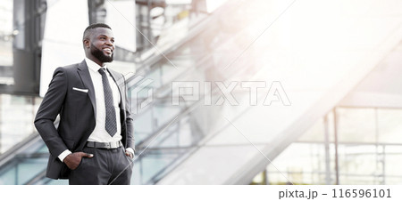 Successful Business. Confident African Businessman Standing Holding Hands In Pockets In Urban Area Outside. Free Space Successful Business. Confident African Businessman Standing Holding Hands In Pockets In Urban Area Outside. Free Space 116596101