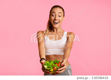 Excited Slim Woman Holding Vegetable Salad In Bowl Standing On Yellow Studio Background. Free Space 116596410