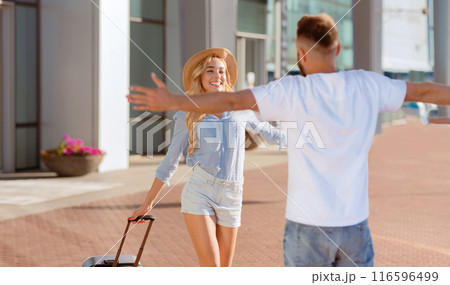 Meet And Greet Concept. Back view portrait of man greeting woman with open arms after parting Meet And Greet Concept. Back view portrait of man greeting woman with open arms after parting 116596499