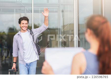 Long-awaited date. Young woman with name board meeting cheerful millennial guy in airport, free space 116596765