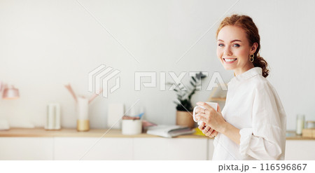 Break at work. Female employee drinking morning coffee, leaning on desk, crop Break at work. Female employee drinking morning coffee, leaning on desk, crop 116596867
