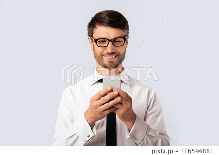 Positive Businessman Texting On Mobile Phone Standing Over White Background. Studio Shot, Free Space 116596881