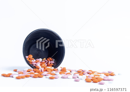 Multicolor pills spilling out of spilled from black plastic box on white background. closeup Multicolor pills spilling out of spilled from black plastic box on white background. closeup 116597371