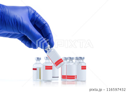 Hand in blue glove holding vaccine vials isolated on white background. Closeup Hand in blue glove holding vaccine vials isolated on white background. Closeup 116597432