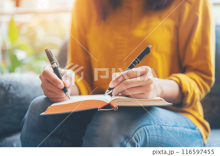 Young woman cozy sweater writing in journal candlelight softly lit cafe Young woman cozy sweater writing in journal candlelight softly lit cafe 116597455