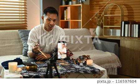 Fortune teller recording video for blog with smartphone. Forecasting and predicting online concept Fortune teller recording video for blog with smartphone. Forecasting and predicting online concept 116597604