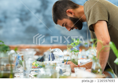 Creative director designing on a table full of colors and a blue wall behind with copy space Creative director designing on a table full of colors and a blue wall behind with copy space 116597693