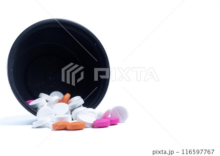 Pills spilling out of a black plastic container leaning against a white background. Medical health care concept. 116597767