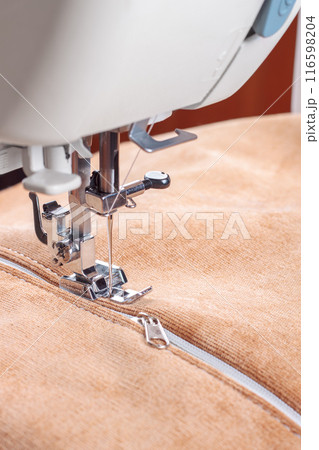Modern sewing machine special presser foot with beige velveteen fabric and zipper, closeup 116598204