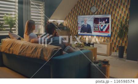 Caucasian couple watches news broadcast about United States Election Day on TV 116598574