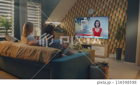Man and woman watch news broadcast on big TV screen sitting on sofa at home Man and woman watch news broadcast on big TV screen sitting on sofa at home 116598598