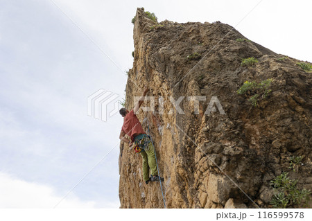 A man is climbing a rock wall 116599578
