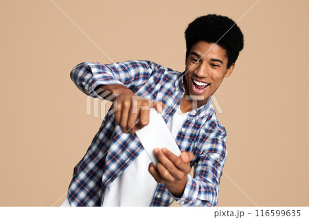Excited teen guy playing on smartphone online game over white background Excited teen guy playing on smartphone online game over white background 116599635