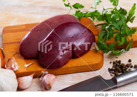 Raw pork kidney on wooden surface with garlic and greens 116600571