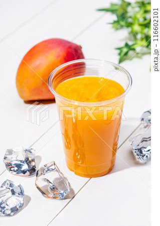 白板のテーブルにプラスチックのコップにはいったマンゴースムージー 116602101