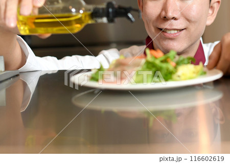 オリーブオイルをサラダにかける男性料理人 116602619
