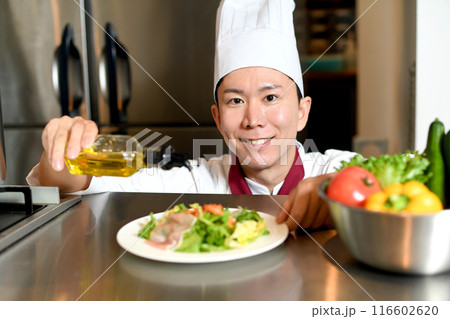 オリーブオイルをサラダにかける男性料理人 116602620