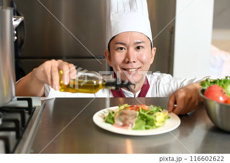 オリーブオイルをサラダにかける男性料理人 116602622