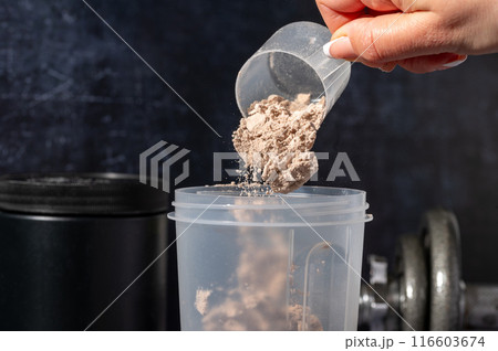 pouring chocolate protein powder in a shaker. Food supplements. Dark background. Bodybuilding, fitness, gym. 116603674